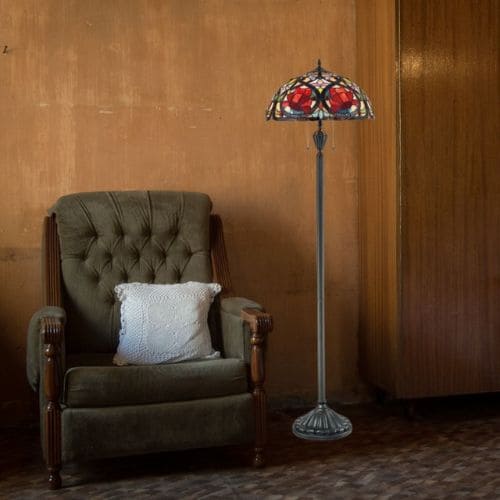 Lampadaire Tiffany Larissa de la marque Quoizel en bronze, couleur rouge, à côté d'un fauteuil dans un salon.