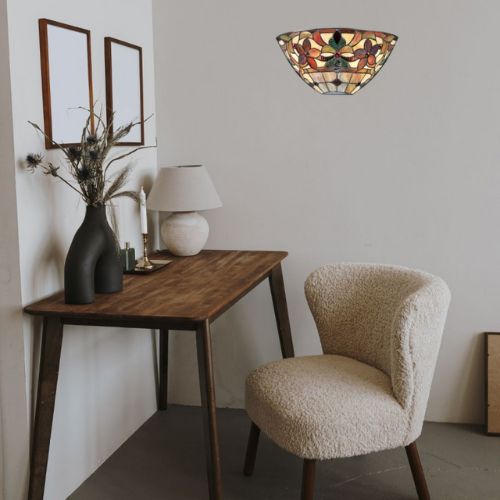 Applique Tiffany Kami du fabricant Quoizel, aux couleurs marron, orange, vert, bronze, à proximité d'un fauteuil et d'une table en bois
