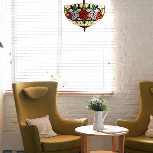 Plafonnier de style Tiffany Rosy de la marque MyTiffany en fer et en verre, situé au-dessus d'un fauteuil aux tons jaunes/bronze et d'une table basse